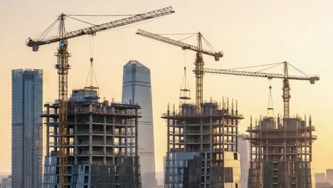 skyscrapers under construction with cranes against a sunset sky