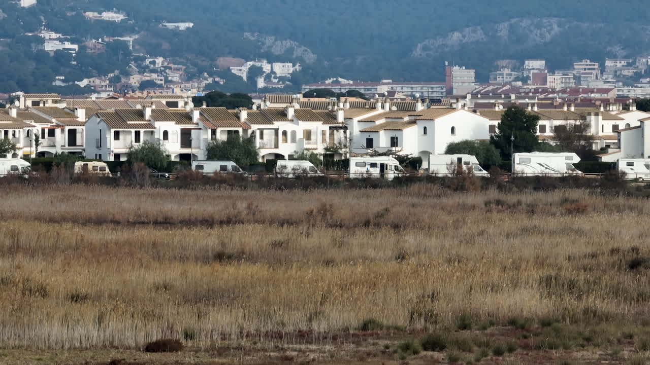 fila de autocaravanas autocaravanas estacionadas en una calle tranquila junto a un prado herboso que visita la ubicación costera