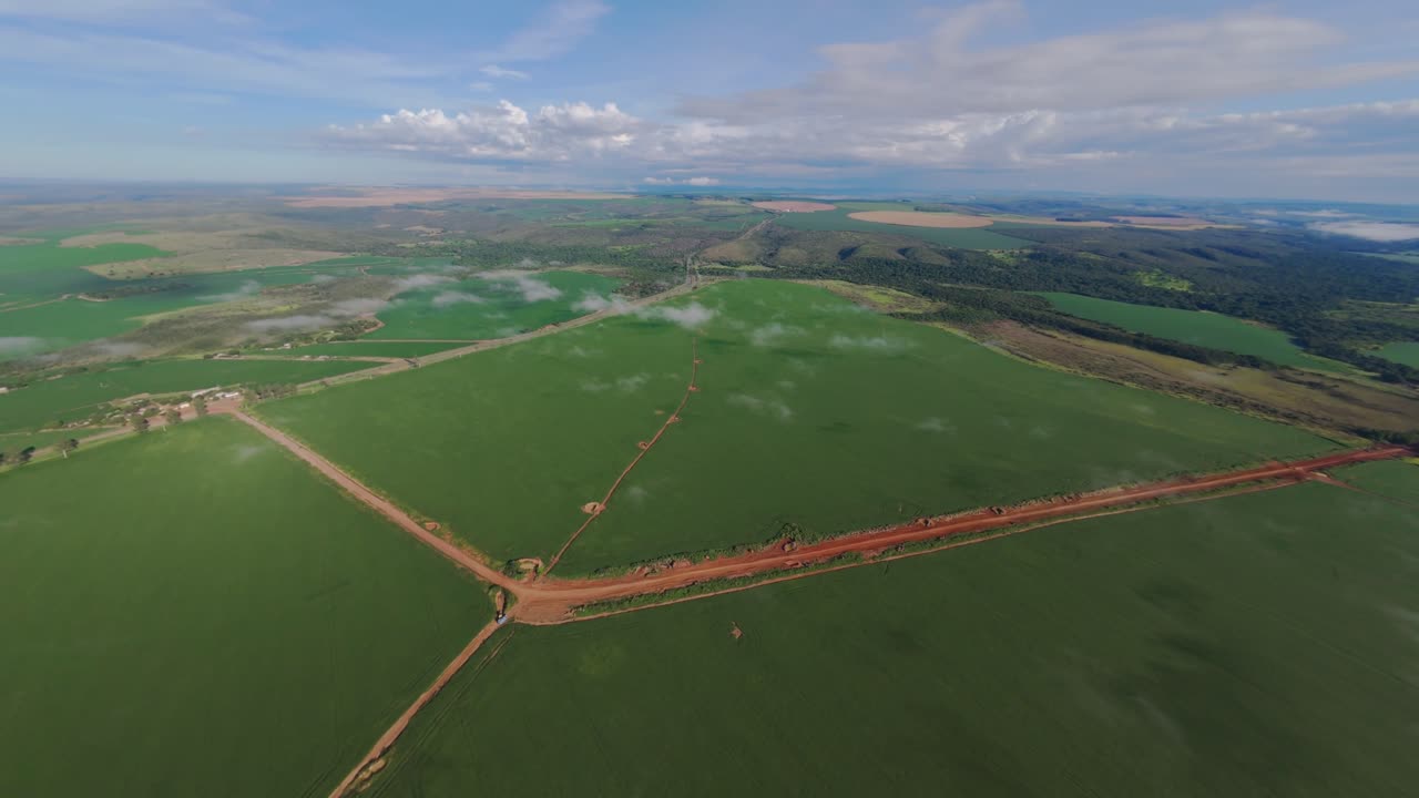 Aerial view of a soy bean plantation in Goias, Brazil, revealing a network of dirt roads crossing the vast green expanse of crops, creates contrast against the landscape shot from high altitude