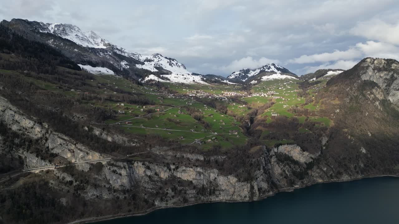 las sombras de las nubes pasan por encima de las casas en la ladera de prado herboso en walensee, suiza.