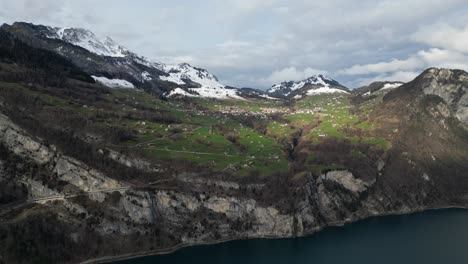 Las-Sombras-De-Las-Nubes-Pasan-Sobre-Casas-En-La-Ladera-De-Una-Pradera-Cubierta-De-Hierba-En-Walensee,-Suiza