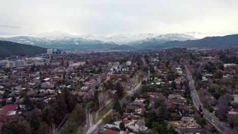 dolly in aerial view of las condes on a cloudy day with the snowy andes mountain range in the background, santiago, chile