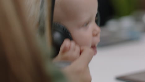 close-up-young-caucasian-business-woman-mother-playing-with-baby-daughter-at-work-playful-toddler-wearing-headphones-enjoying-loving-mom-successful-motherhood-in-office-workplace