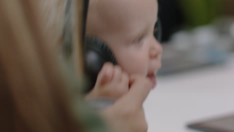 close up young caucasian business woman mother playing with baby daughter at work playful toddler wearing headphones enjoying loving mom successful motherhood in office workplace