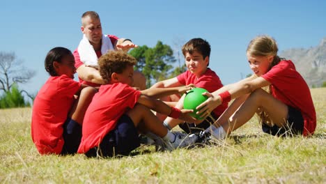 entrenador ayudando a los niños mientras hacen ejercicio en el campamento de entrenamiento