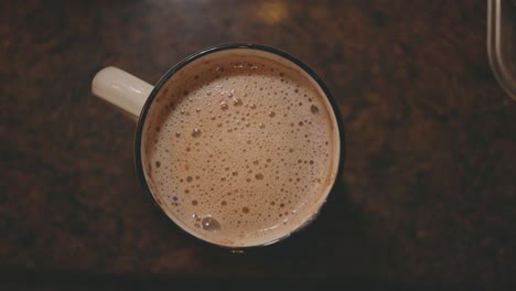 taza de bebida de chocolate espumoso caliente en la mesa de la cocina para el desayuno - tiro superior