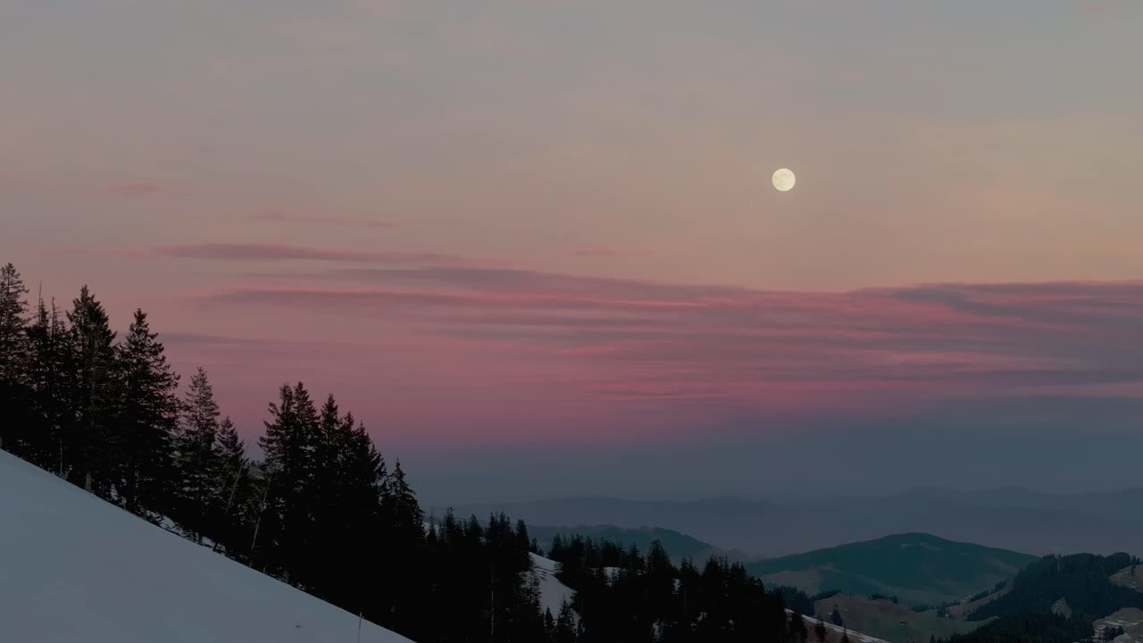 눈 인 산맥의 실루 위에서 해가 뜨는 조용한 분위기를 드러내는 화려한 드론 영상