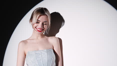 smiling woman in a silver dress under spotlight