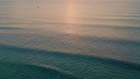 Majestic ocean surface rippling under evening sunlight aerial. Golden sunset