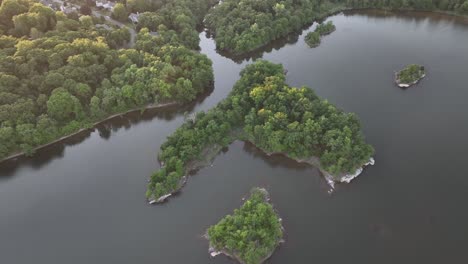 an aerial view over calm waters with small islands with green trees on a sunny day