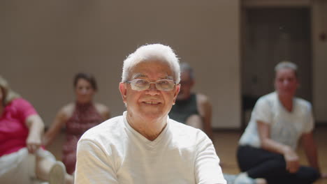 Happy-senior-man-sitting-on-floor-after-dance-class-in-ballroom