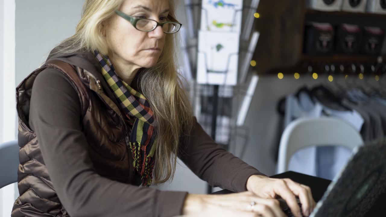 Woman working on laptop in cafe with coffee