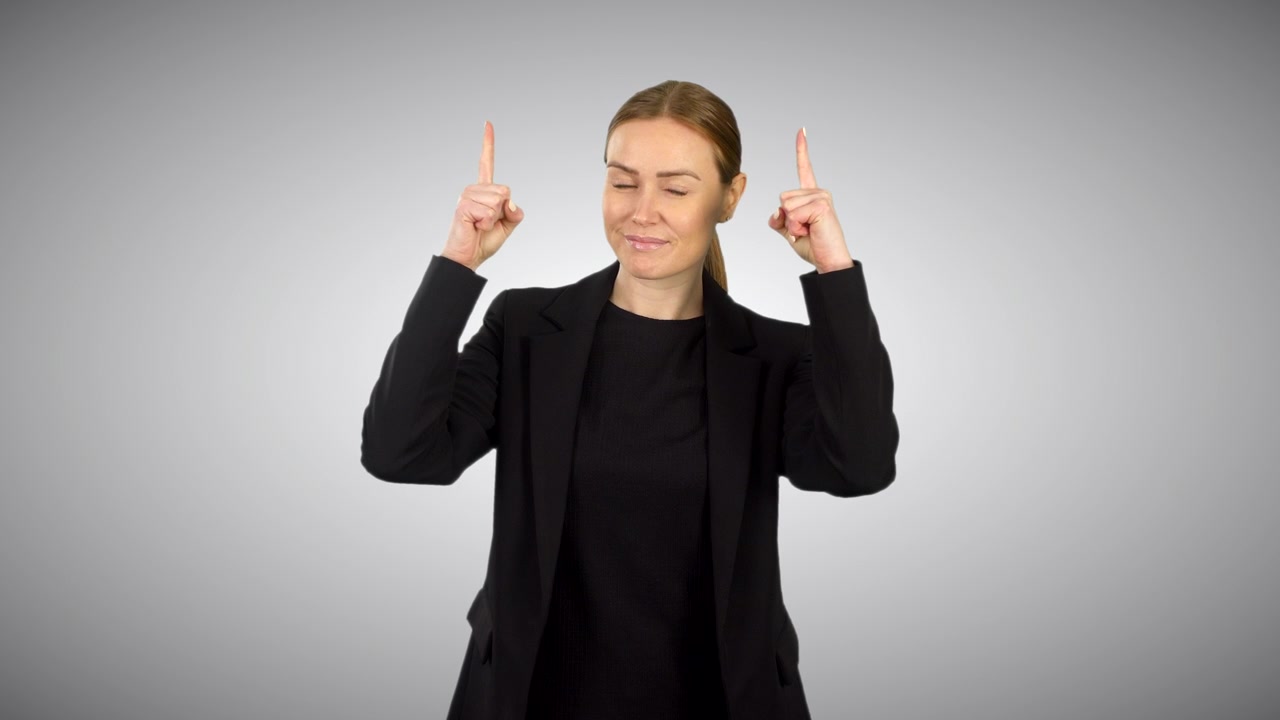 Uma mulher de negócios vestida de preto apontando para cima com dois dedos