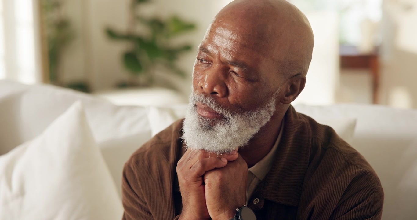 Thoughtful Senior Man Sitting on Sofa at Home