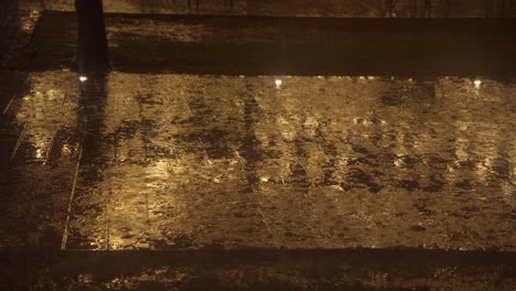 rain by night, raindrops on street sidewalk floor with light reflections on pavement