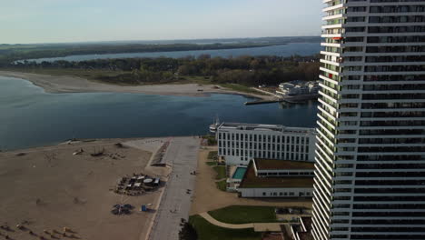 Sideways-flight-on-beach-with-hotel-complex-and-port-in-backgorund