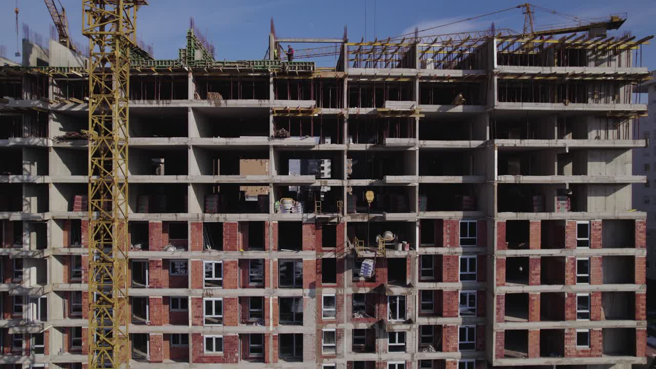 grúa que entrega materiales de construcción para que los trabajadores construyan un edificio residencial