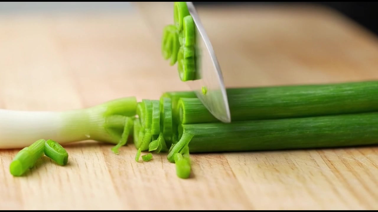 Chef snijdt verse lente-uitjes op een houten snijplank