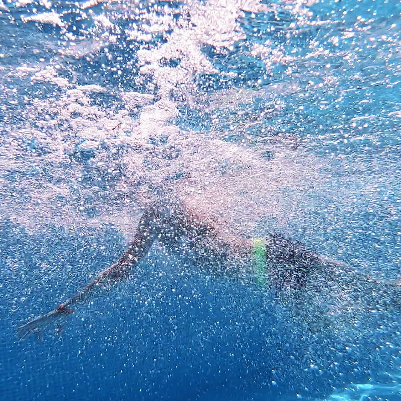 Boy jump into the blue clear water making many bubbles. Young boy jumping underwater into the swimming pool. Underwater camera.