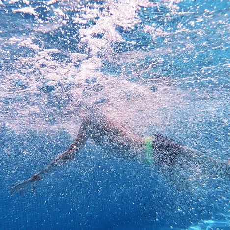 boy jump into the blue clear water making many bubbles. young boy jumping underwater into the swimming pool. underwater camera.