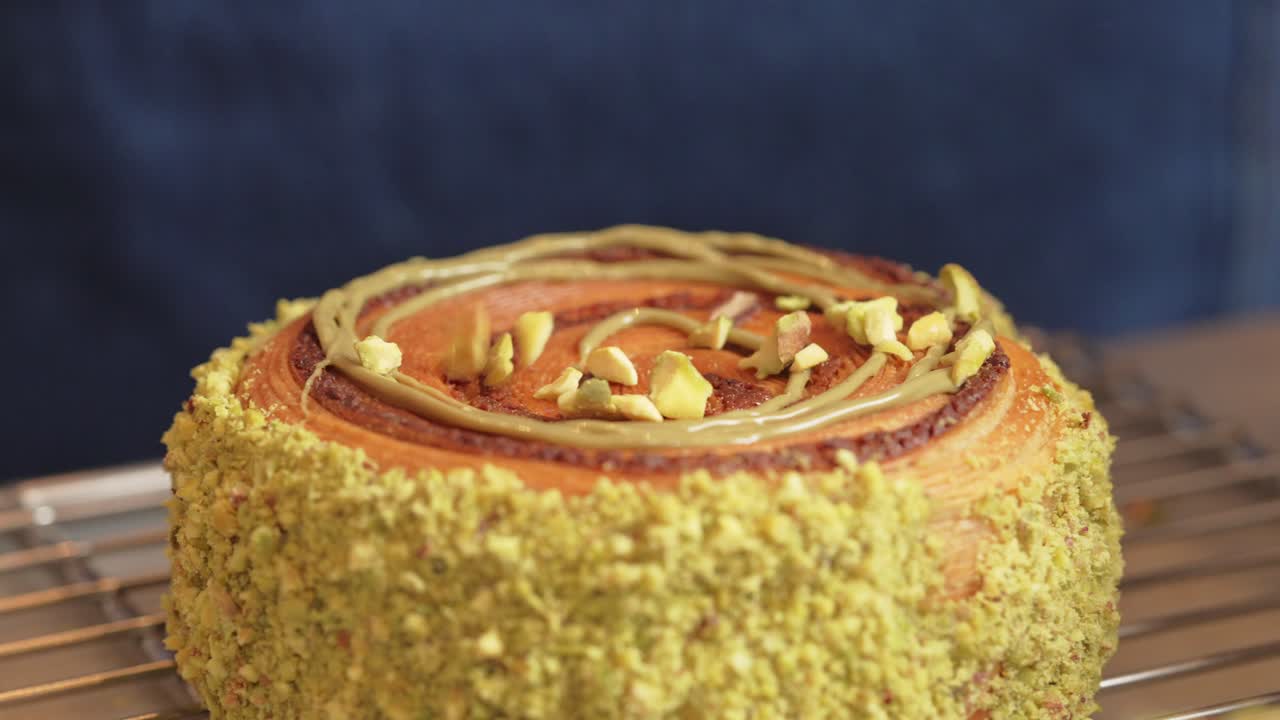 donut croissant de pistacho siendo decorado cubriendo con trozos de pistacho