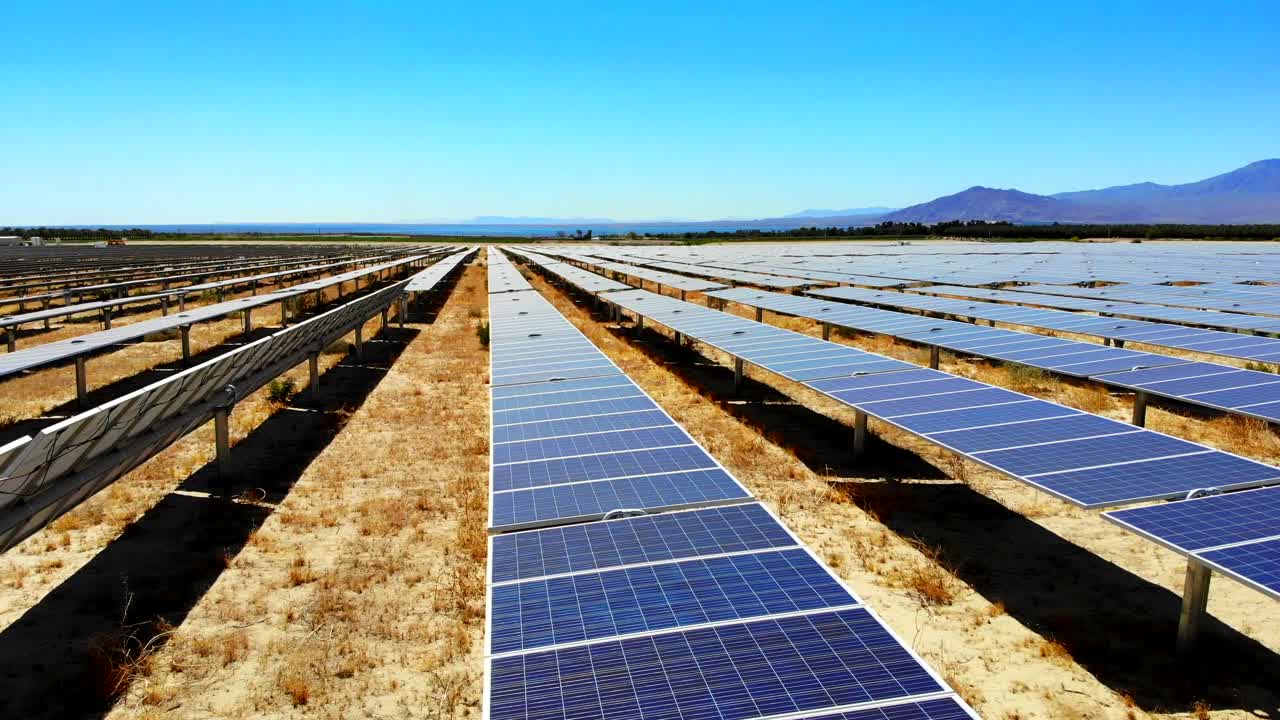 granja solar fotovoltaica lateral aérea 4k drone barrer y elevarse con mar salton en la distancia en el desierto de california