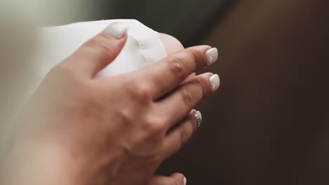 lady in white dress with stylish manicure holds hand on knee