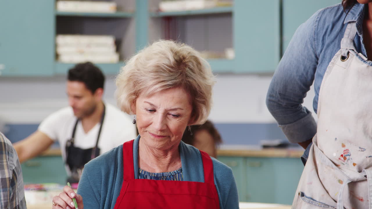 grupo de ancianos jubilados que asisten a clases de arte en un centro comunitario con un maestro