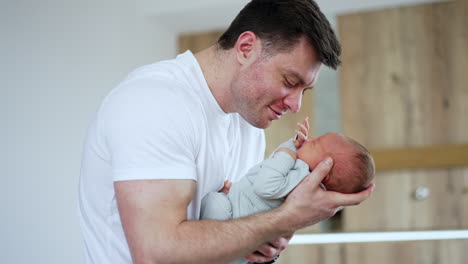 communication of father and his newborn baby. caucasian man holds a tiny child in front of him.