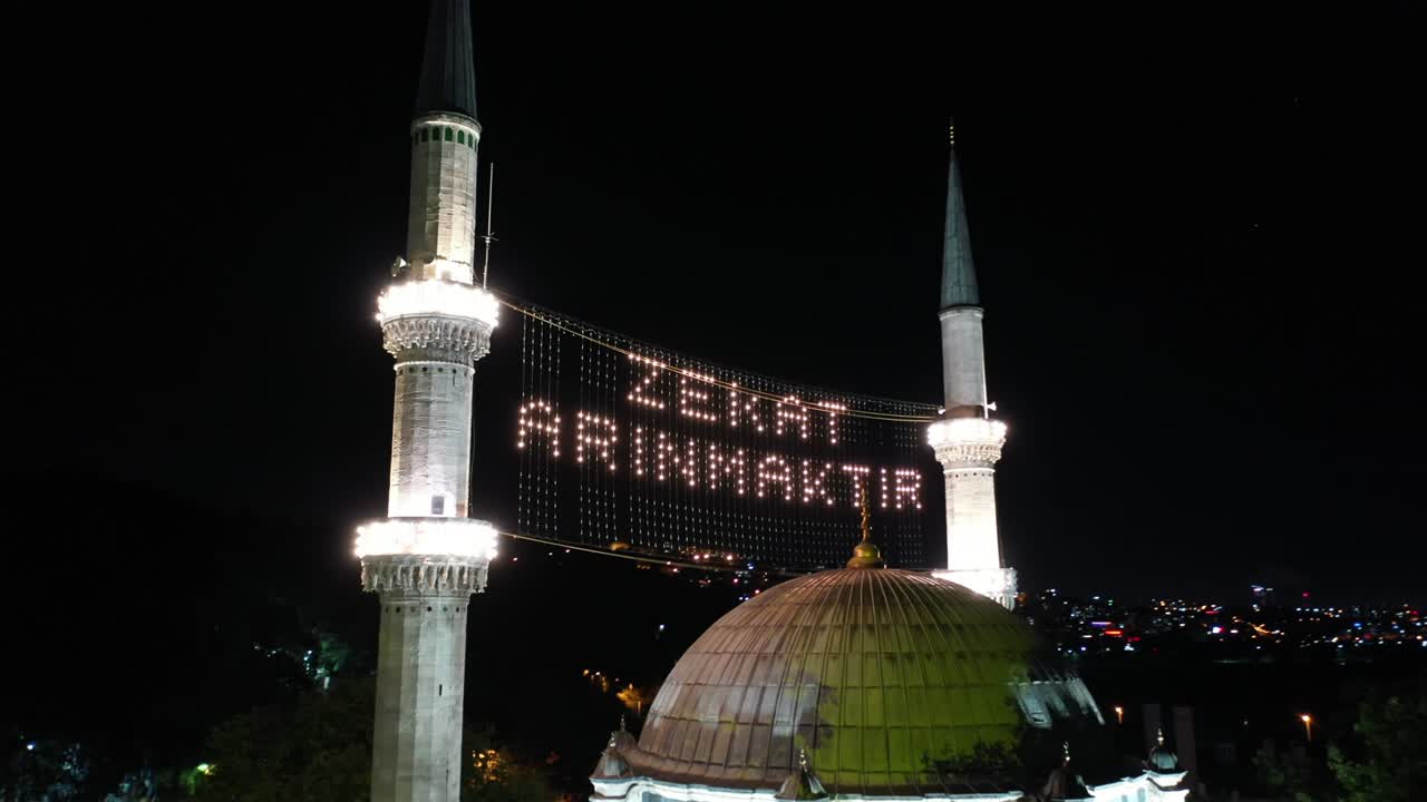 Eyüp Sultan Camii'nin havadan gece görünümü. "Sadaka arındırılmıştır." yazıyor.