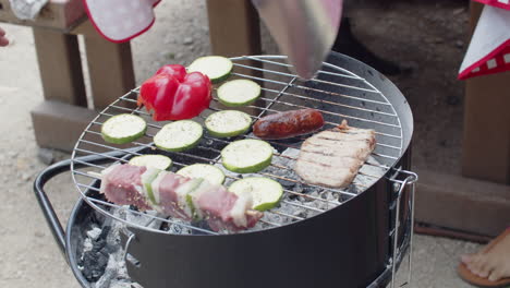 zbliżenie nierozpoznawalnego mężczyzny machającego kawałkiem kartonu nad grillem