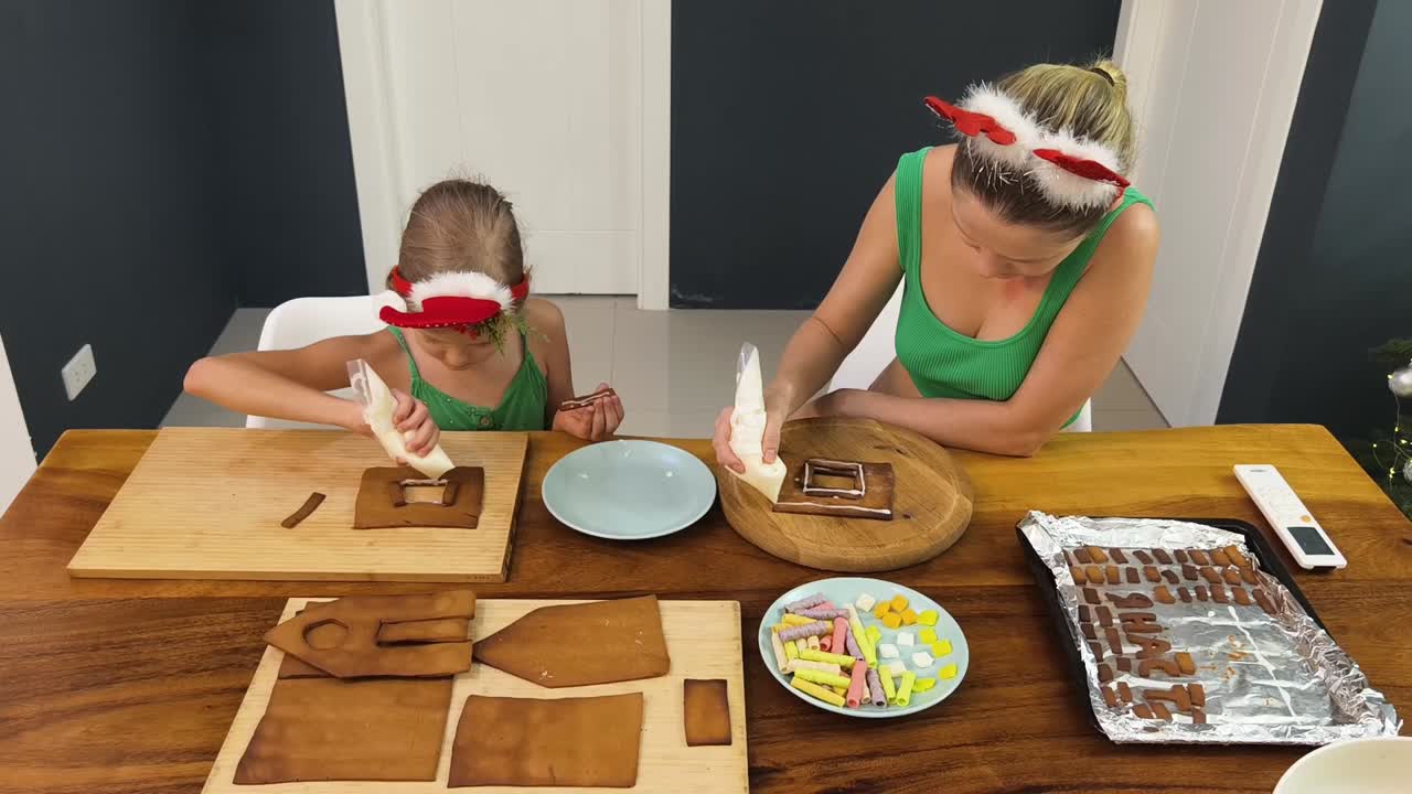madre e hija decorando una casa de pan de jengibre