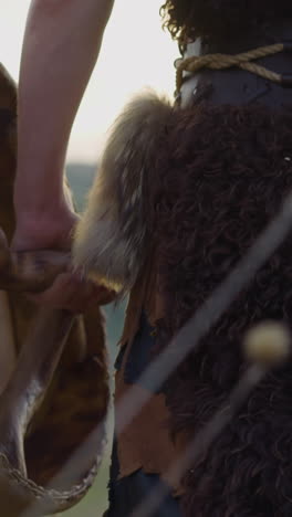 shaman in furry clothes walks holding ritual drum along hilly valley close backside view. ritual musical instrument. altai mystical culture