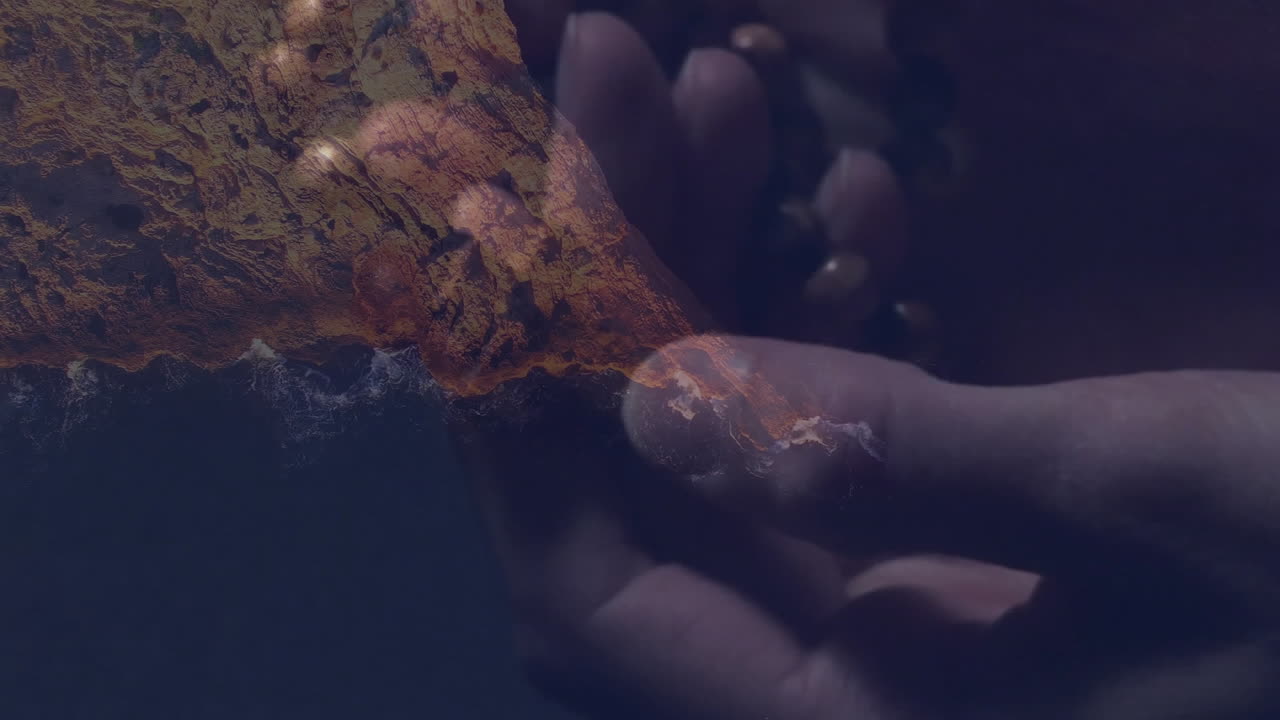 Holding beads, hands over abstract textured landscape, creating artistic composition