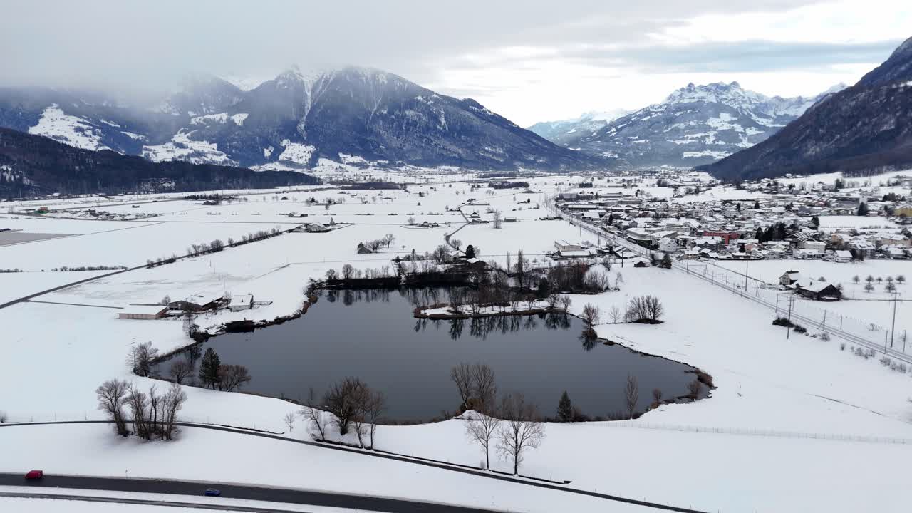 fotografía aérea del lago rodeado de un paisaje invernal nevado y los alpes suizos en el fondo
