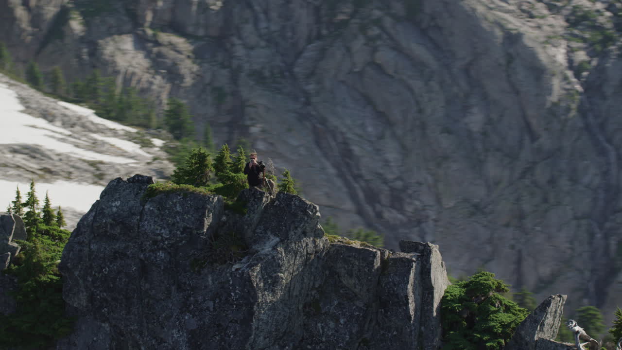 사진작가는 산등성이에서 전화 사진을 찍고 샤카를 던집니다. 팀 더칸 와이드 추적 헬리콥터는 시계 반대 방향으로 느린 궤도를 돌고 있습니다.