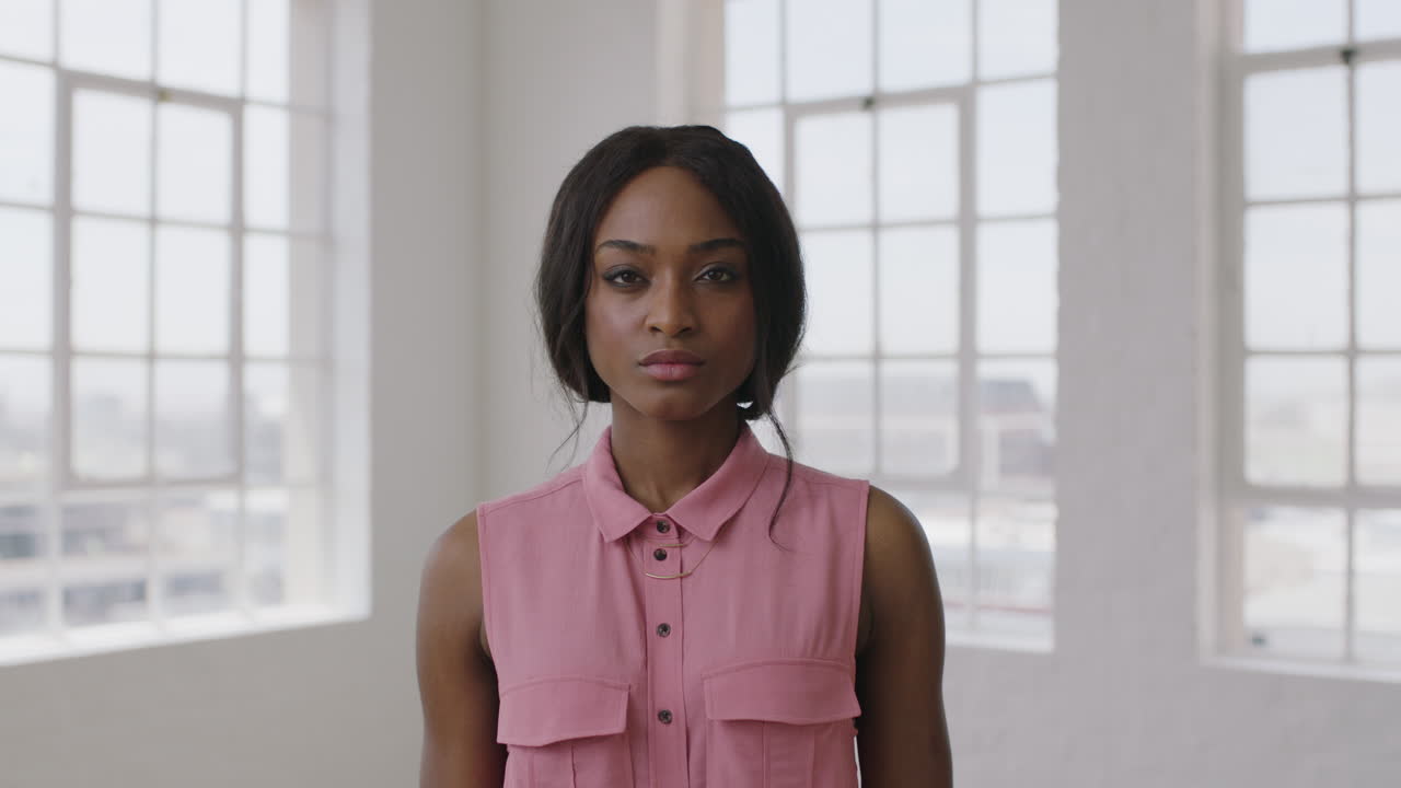 ritratto in slow motion di una giovane donna afroamericana alla moda che guarda seriamente alla telecamera indossando una camicetta rosa