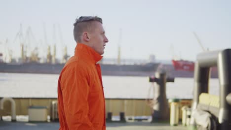 harbor worker in orange uniform is walking on cargo harbor site. slow motion