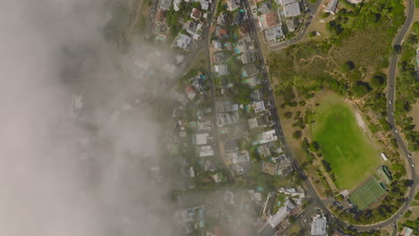 Volar-Sobre-La-Ciudad-Costera,-Visibilidad-Limitada-Debido-A-La-Niebla-Que-Se-Eleva-Desde-El-Mar.-Viviendas,-Calles-Y-Zonas-Deportivas-En-Barrio-Urbano.-Ciudad-Del-Cabo,-Sudáfrica