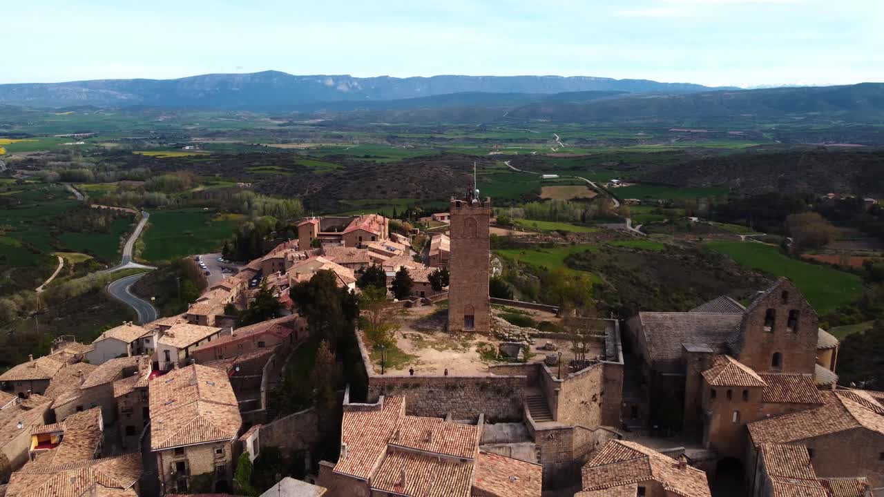 Aerial view pulling back to reveal the medieval village of Sos del Rey Católico, perched on a hill with historic stone houses.