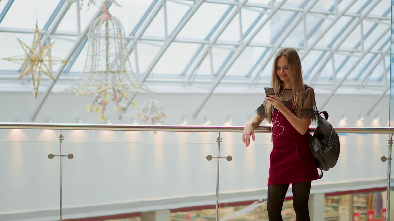 una bloguera sonriente escuchando sus canciones favoritas en los auriculares mientras posa para una selfie en la cámara de su teléfono inteligente, una chica hipster disfrutando de la transmisión de radio haciendo fotos para las redes sociales en su móvil.