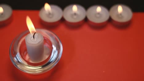 Burning-white-candles-on-a-red-background,-falling-gold-dust