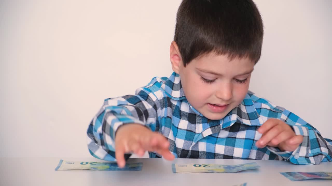 un niño de 4 años cuenta dinero, tiene euros en las manos.