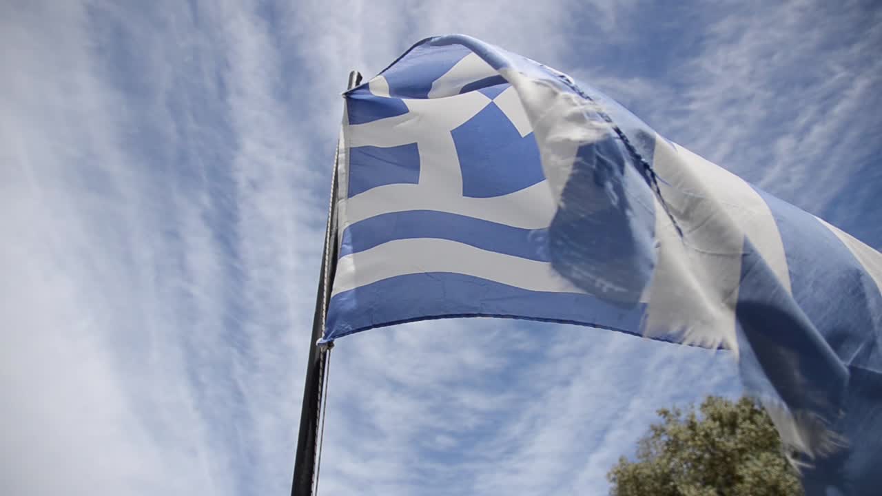 Flag of Greece flying, blue sky in background