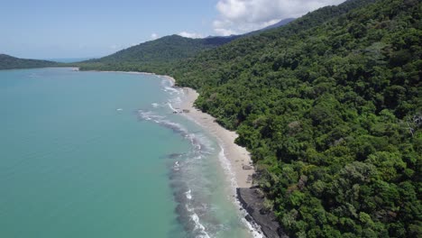 aerial view over turquoise ocean water and lush rainforest in the daintree national park in far north queensland, australia - drone shot