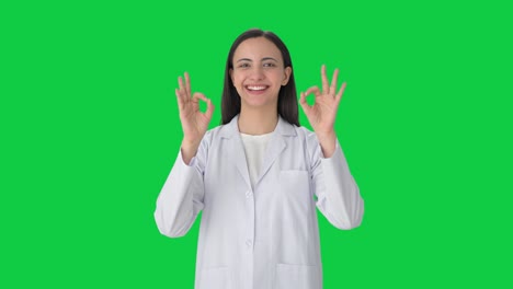 Happy-Indian-female-scientist-showing-okay-sign-Green-screen