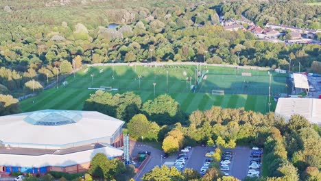 Aerial-ascend-above-school-building-to-reveal-soccer-teams-practice-on-field