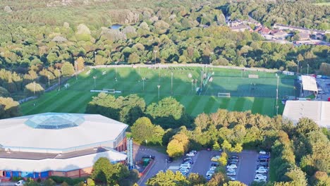 aerial ascend above school building to reveal soccer teams practice on field