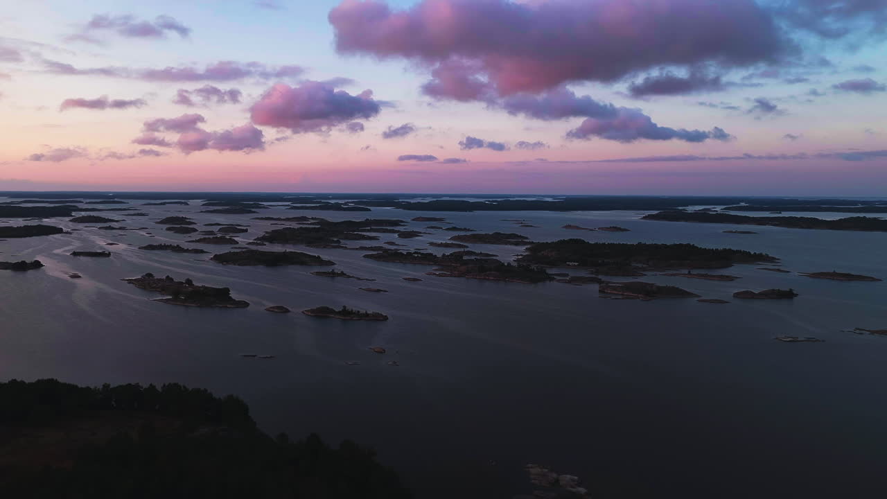 Luftfoto som stiger opp mot små øyer i Skjærgårdens nasjonalpark, Finland, i skumringen.