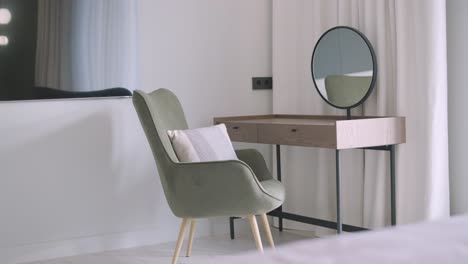 modern dressing table with circular mirror and minimalist design, complemented by a stylish velvet chair in a bright, serene bedroom